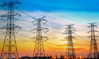 Silhouetted electricity towers against a vibrant sunset