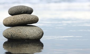 Stack of rocks resting on still water, serene scene.