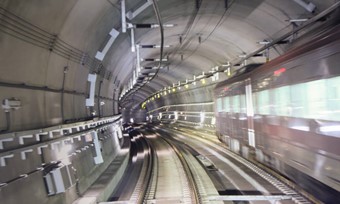 A train moving through a tunnel with a tunnel light illuminating the tracks.