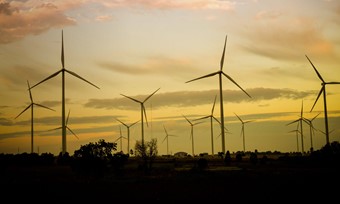 A silhouetted windfarm against an evening sky