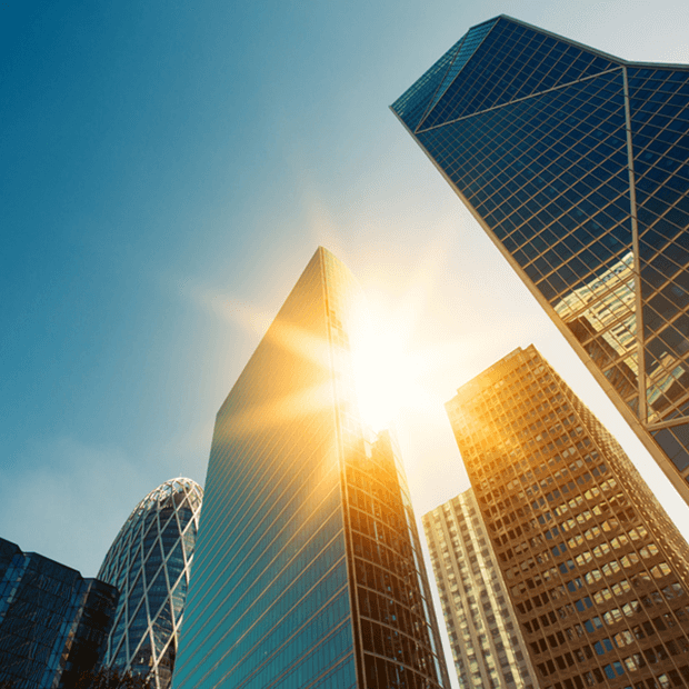A city skyline with sun bursting through the cracks in the buildings