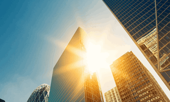 A city skyline with sun bursting through the cracks in the buildings