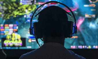 A young man wearing headphones playing games on a large TV